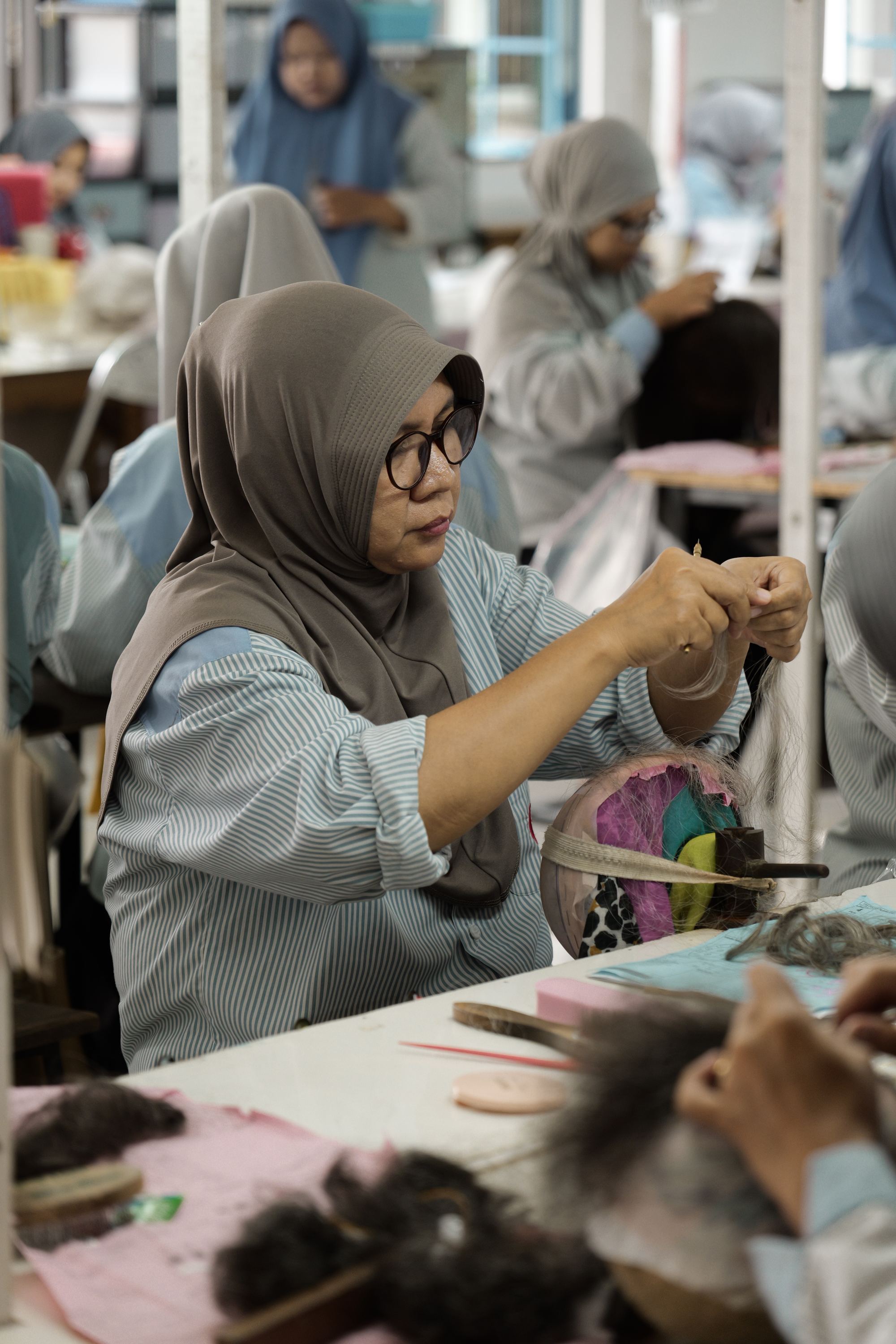 Technician hand-tying knots onto a wig base