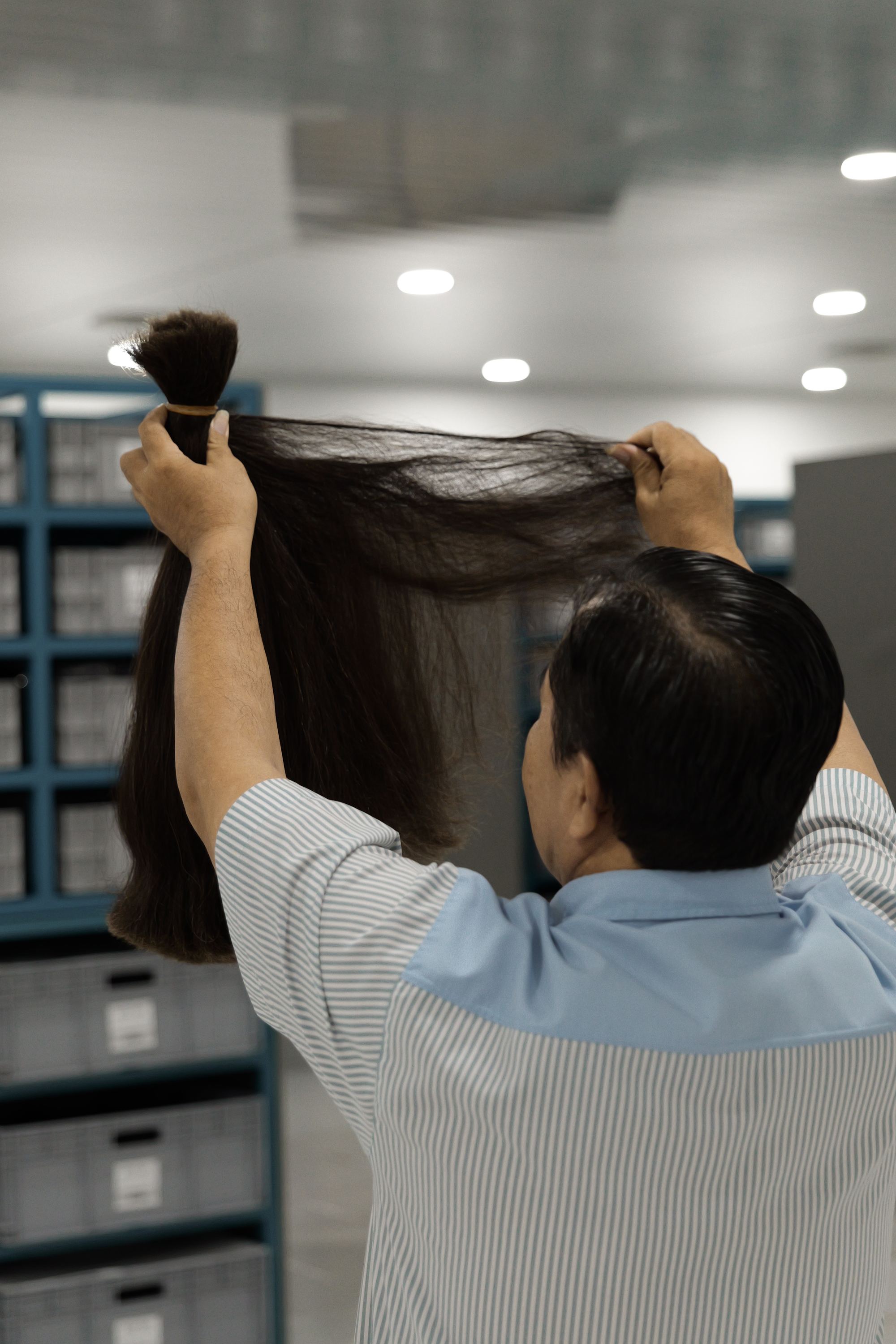 Staff member inspecting a bundle of raw hair