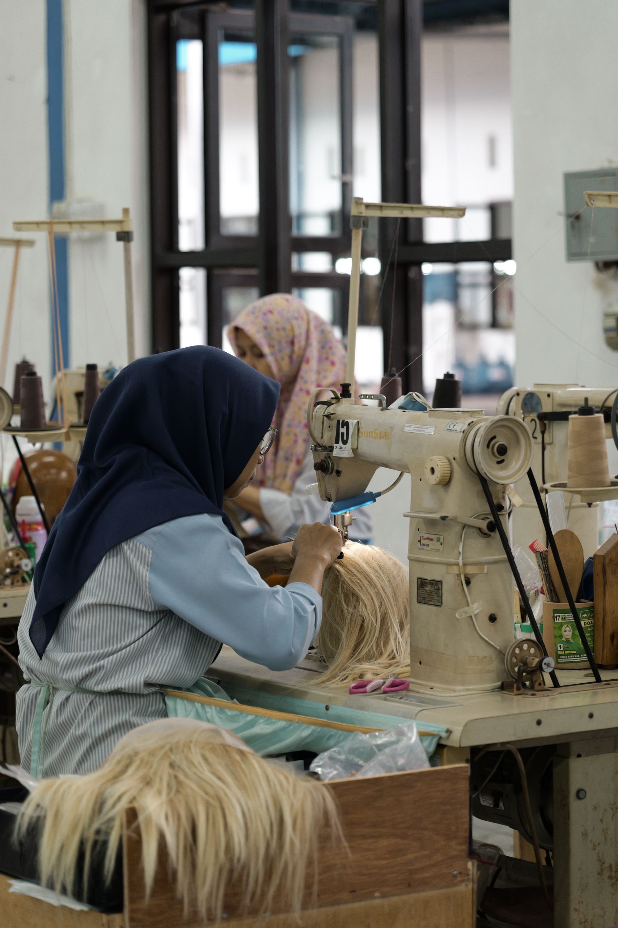 Technician machine-wefting hair on an industrial sewing machine