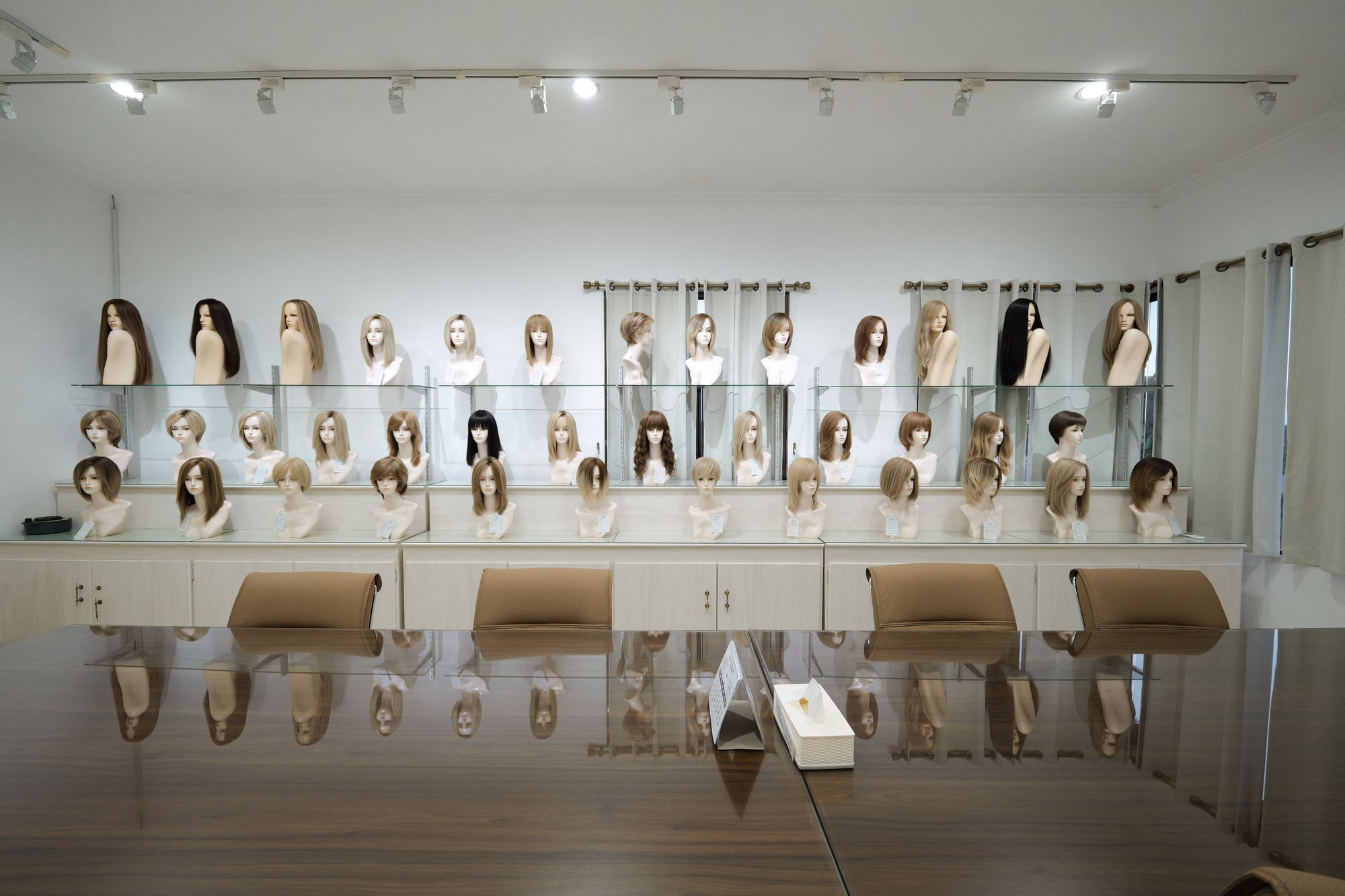 Showroom wall of finished wigs in a range of colours and styles